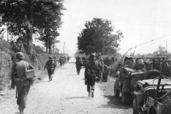 American_Soldiers_Advancing_Past_Jeeps_on_Road_to_Cherbourg_France_30_June_1944