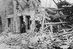 British_Troops_Advance_through_Ruins_of_Demeuville_Normandy_1944