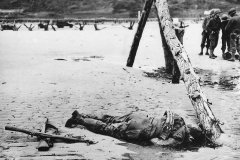 Crossed_rifles_beside_fallen_US_soldier_on_D-Day_Omaha_Beach