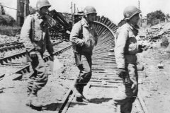 Soldiers_of_327th_Glider_Infantry_Regiment_amid_Ruins_of_Carentan_1944_Normandy